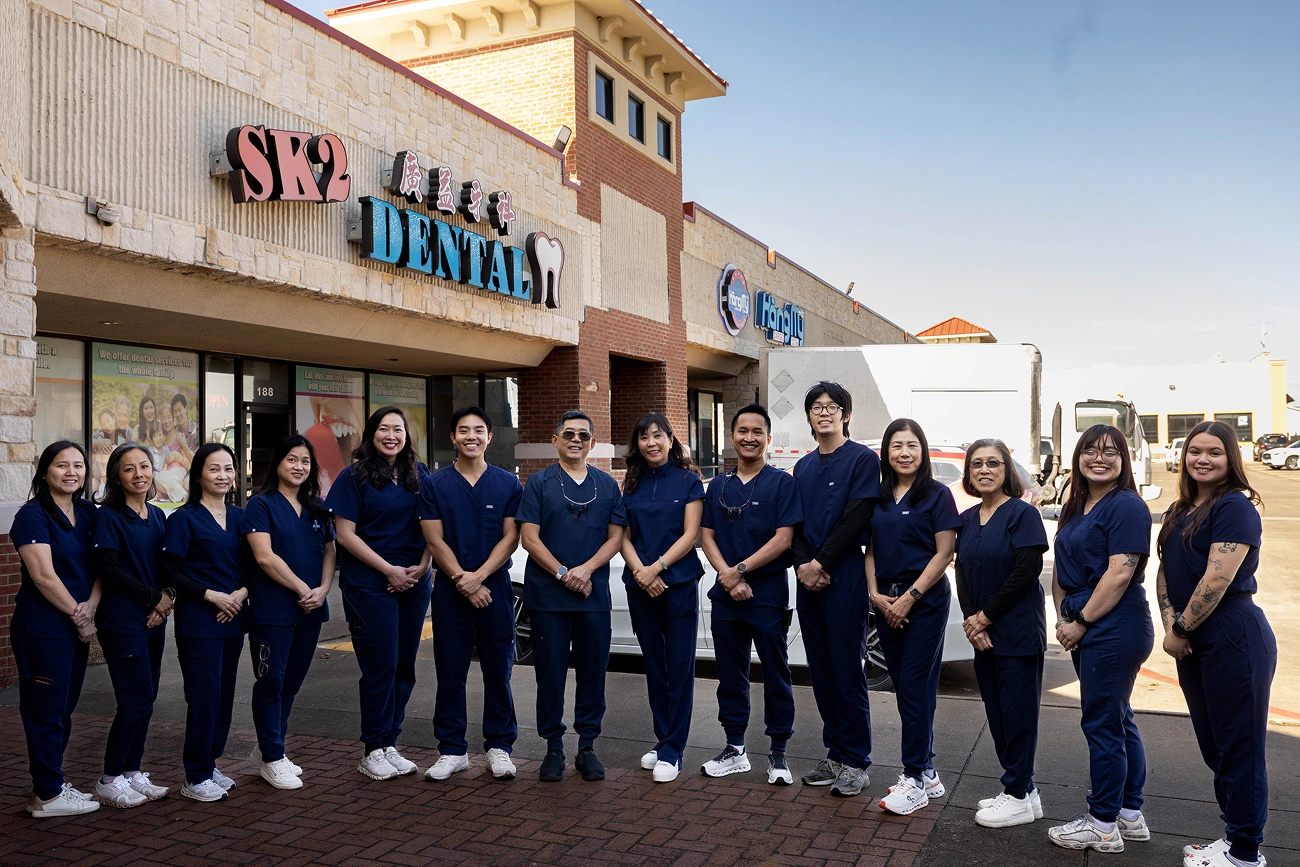 SK2 Dental team members in navy scrubs standing together outside storefront.