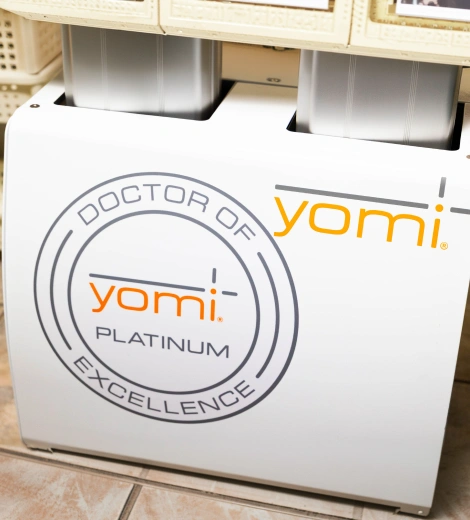 Yomi Platinum dental robot system displayed in clinical setting with branding visible on white equipment.